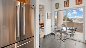 A kitchen with a stainless steel refrigerator and a dining area with a table and chairs.