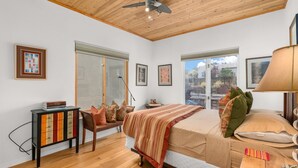 A bedroom with a bed, a wooden ceiling, a window, and a bedside table.
