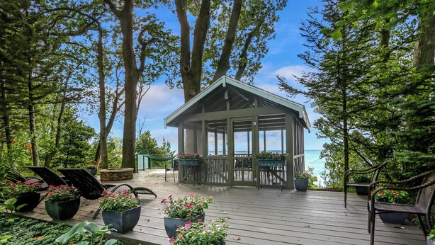 Une terrasse en bois agrémentée de plantes en pot et de mobilier d’extérieur, donnant sur une étendue d’eau.