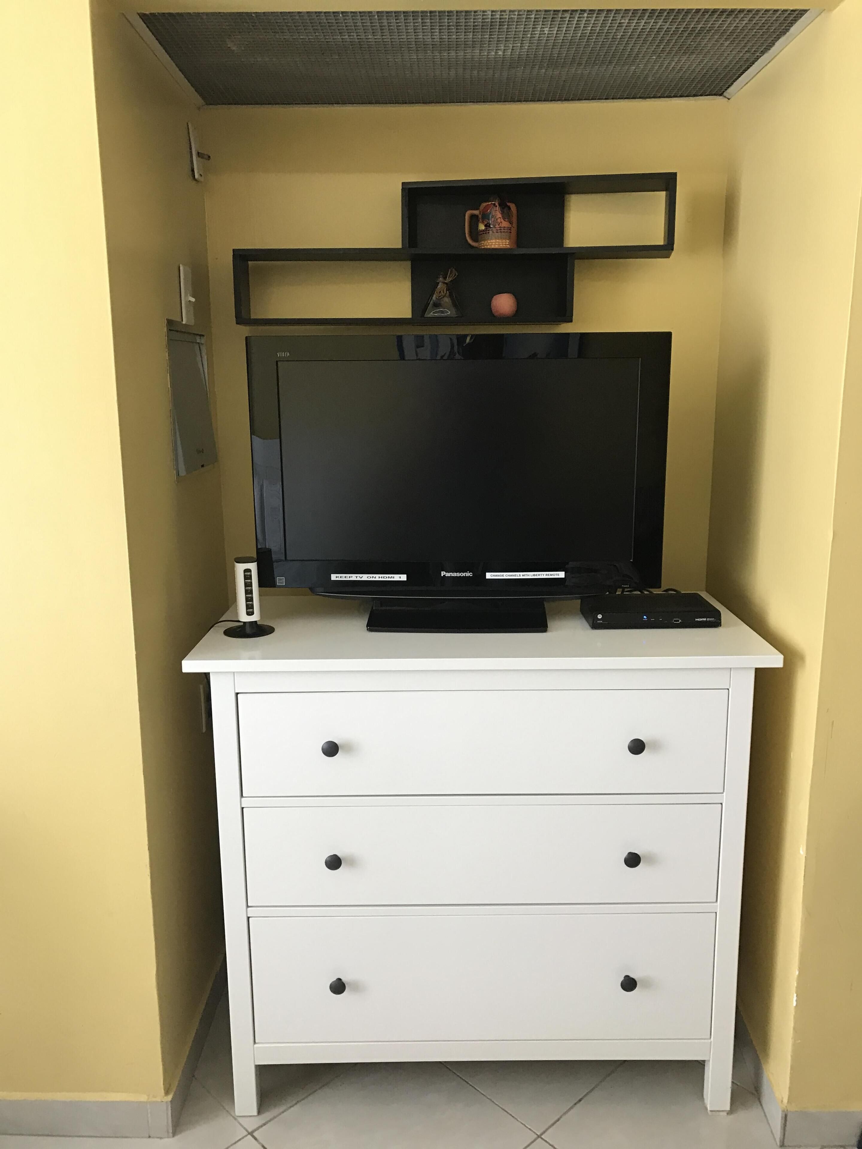 Ein weißes TV-Möbel mit einem Flachbildfernseher, einem DVD-Player und einem kleinen Lautsprecher.