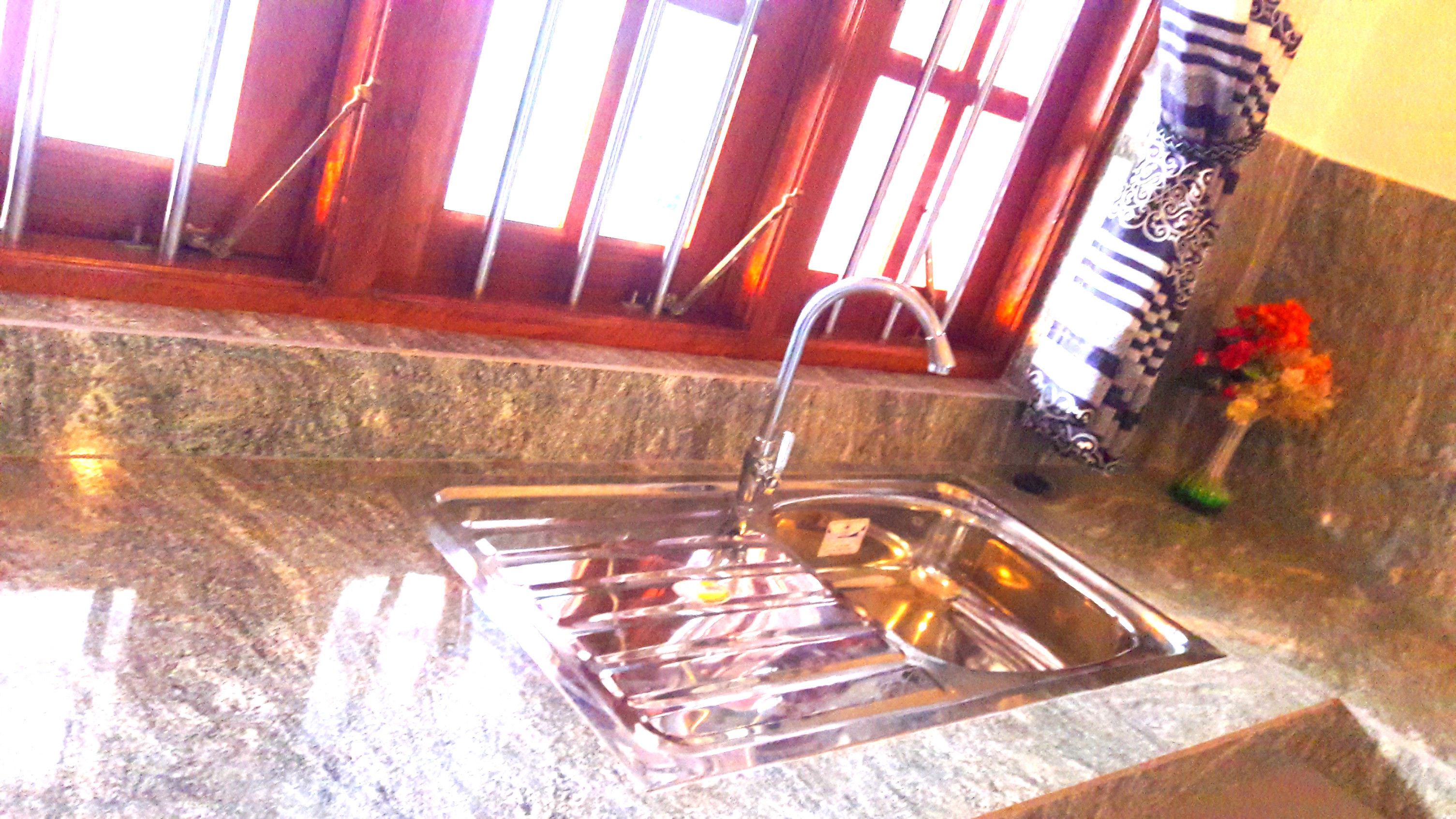 A kitchen with a stainless steel sink, a faucet, and a window with vertical blinds.