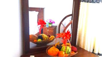 A wooden dresser with a mirror, a basket of fruit, and a small vase with flowers.