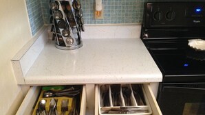 Una cocina con encimera blanca, un recipiente de acero inoxidable para utensilios y un horno Whirlpool.