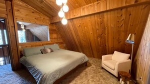 Un dormitorio acogedor con una cama, un sillón y una lámpara.