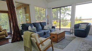 A living room with a sofa, armchair, coffee table, and a view of the outdoors. - Ocean 2 Bay - Ocean/Bay View (Waldport)