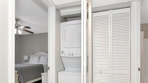 A bedroom with a bed, a washing machine, and a closet with louvered doors. - Lake Front - Ground Level - 2 bedroom 2 bath (Brandon)