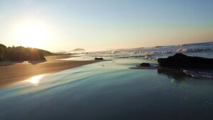 A beach with calm waters, rocks, and a clear sky. - Beautiful serene apartment-saltwater pool, gardens, 200 feet from the beach! (Troncones)