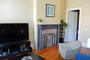 A living room with a flat-screen TV, a fireplace, a door, and a potted plant.