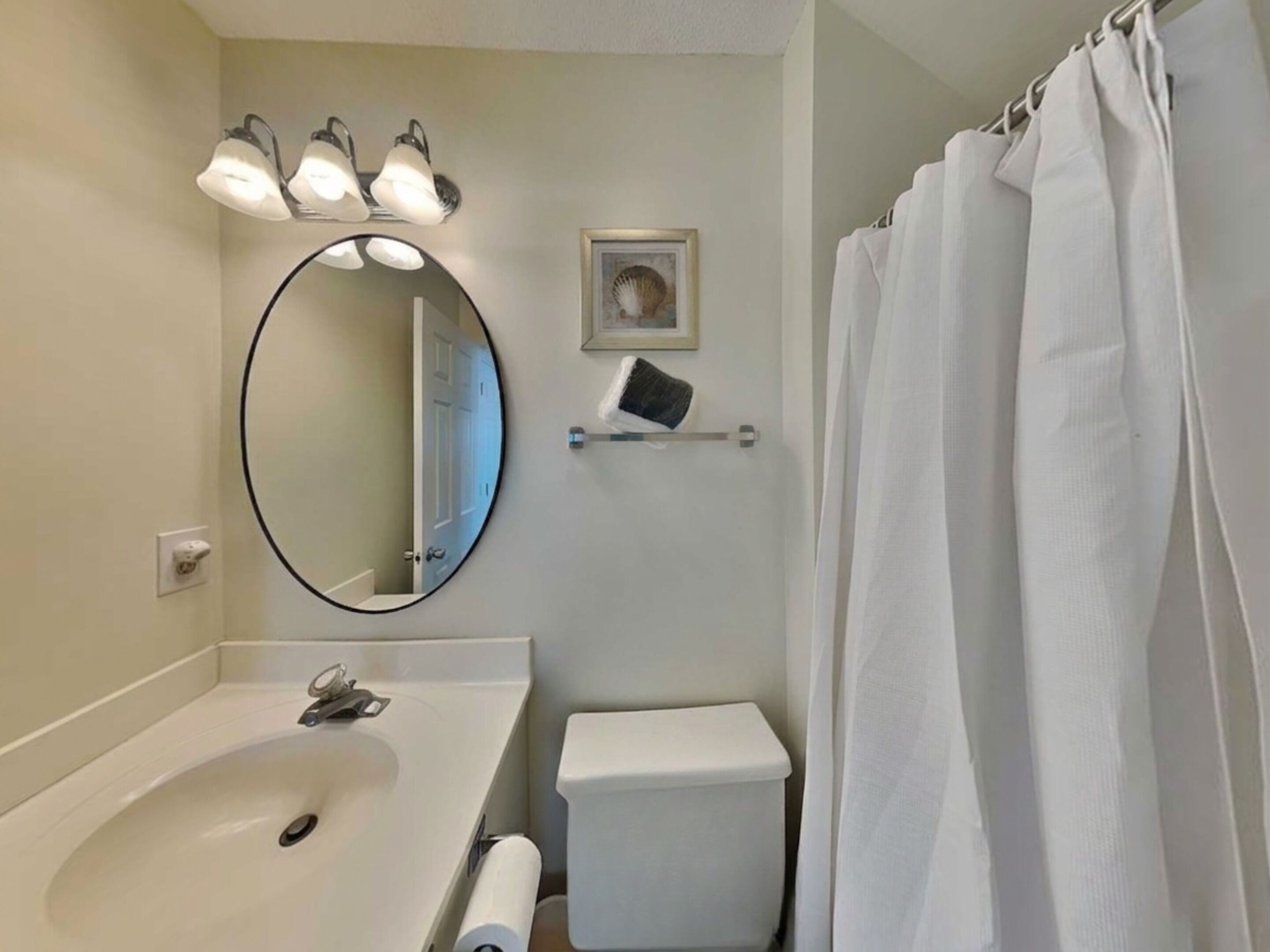 A bathroom with a sink, toilet, and shower curtain.