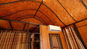 A room with wooden panel walls, a metal staircase, and a white air conditioning unit.