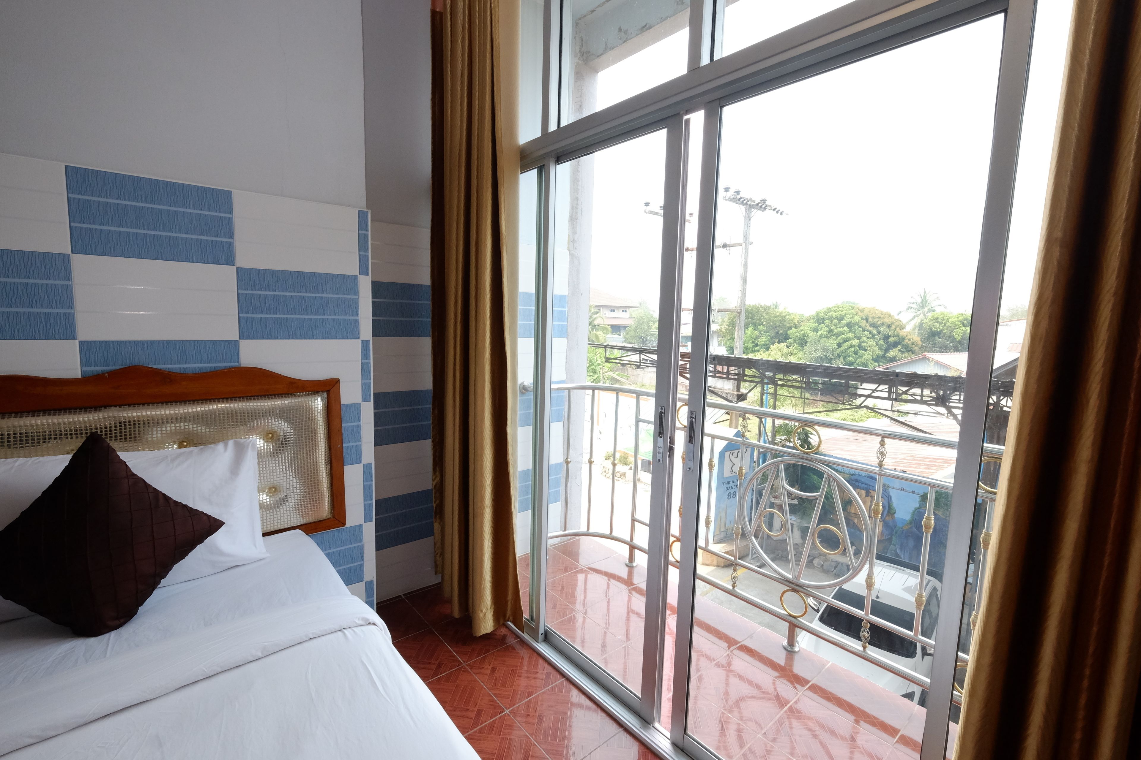 A hotel room with a bed, a view of the balcony, and a window with curtains.