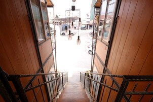 Una escalera de madera que conduce a una calle con luces colgantes y vista de la calle abajo.
