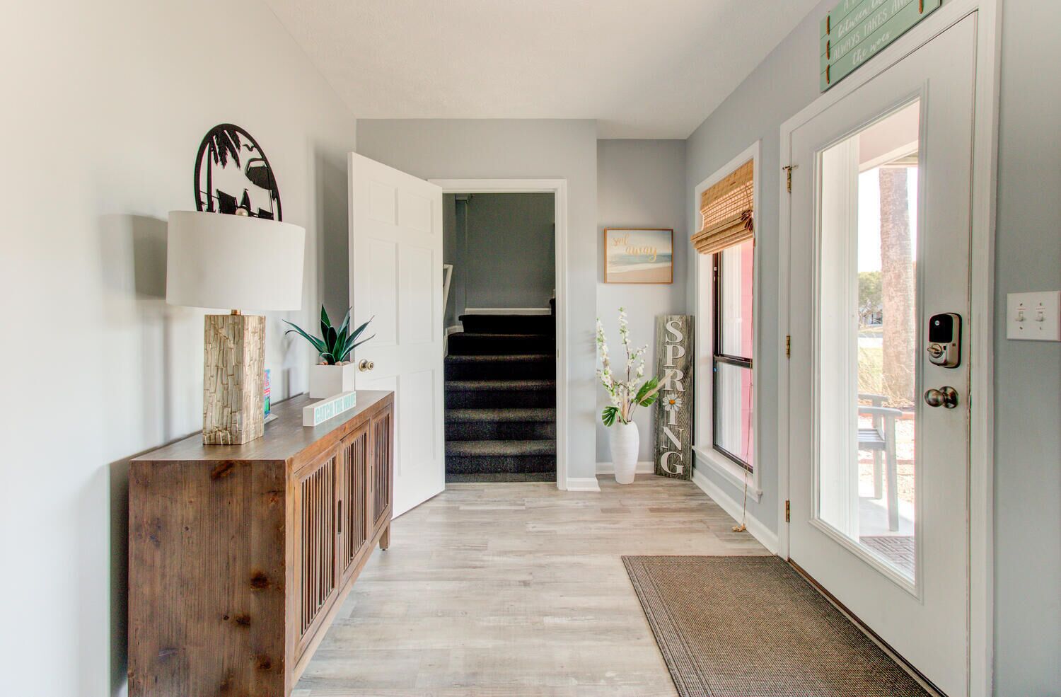 A hallway with a wooden console table, a staircase, and a door with a window.