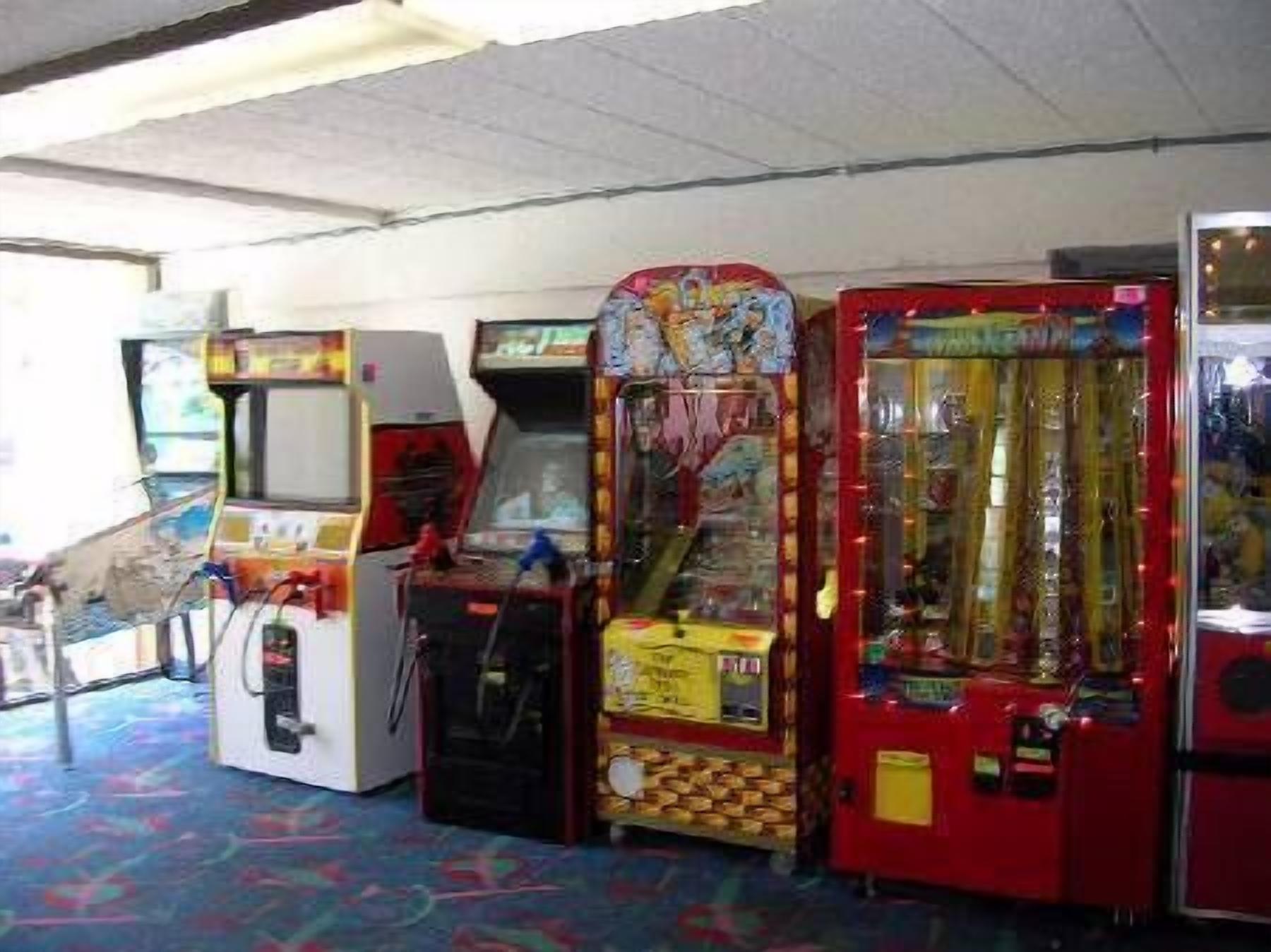 A row of arcade machines in a room with a patterned carpet.
