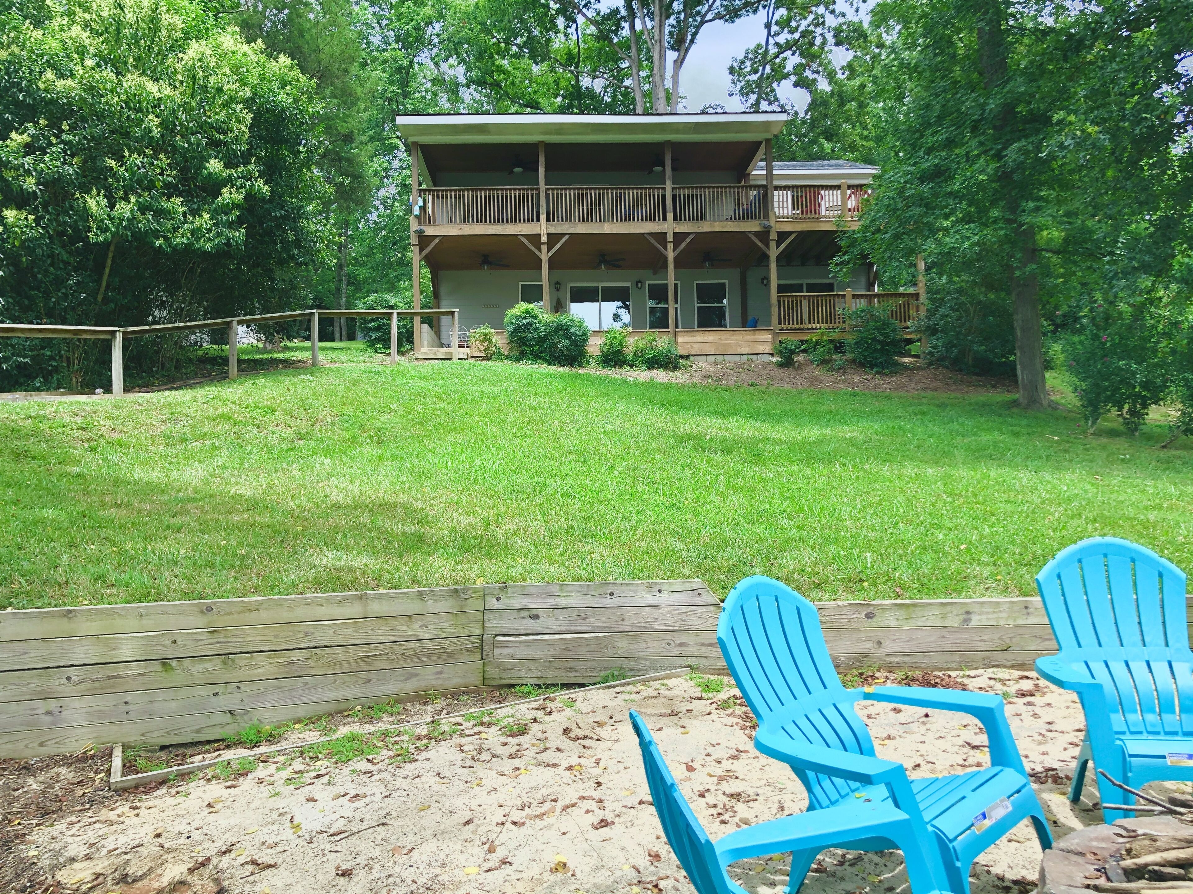 A two-story building with a balcony, surrounded by a grassy yard and trees.