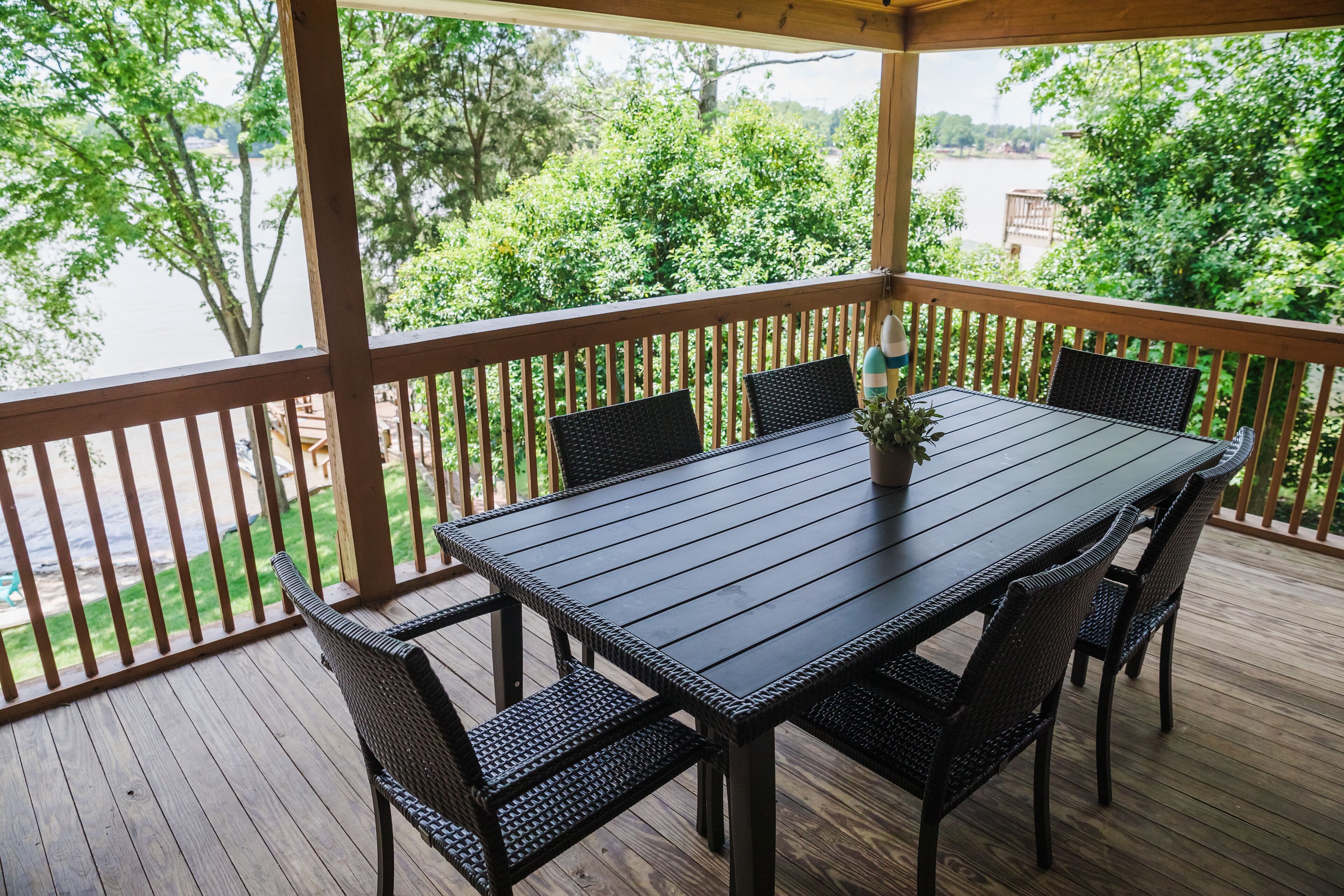 Une terrasse extérieure couverte, dotée d’une table et de chaises en bois, et entourée d’une balustrade en bois.