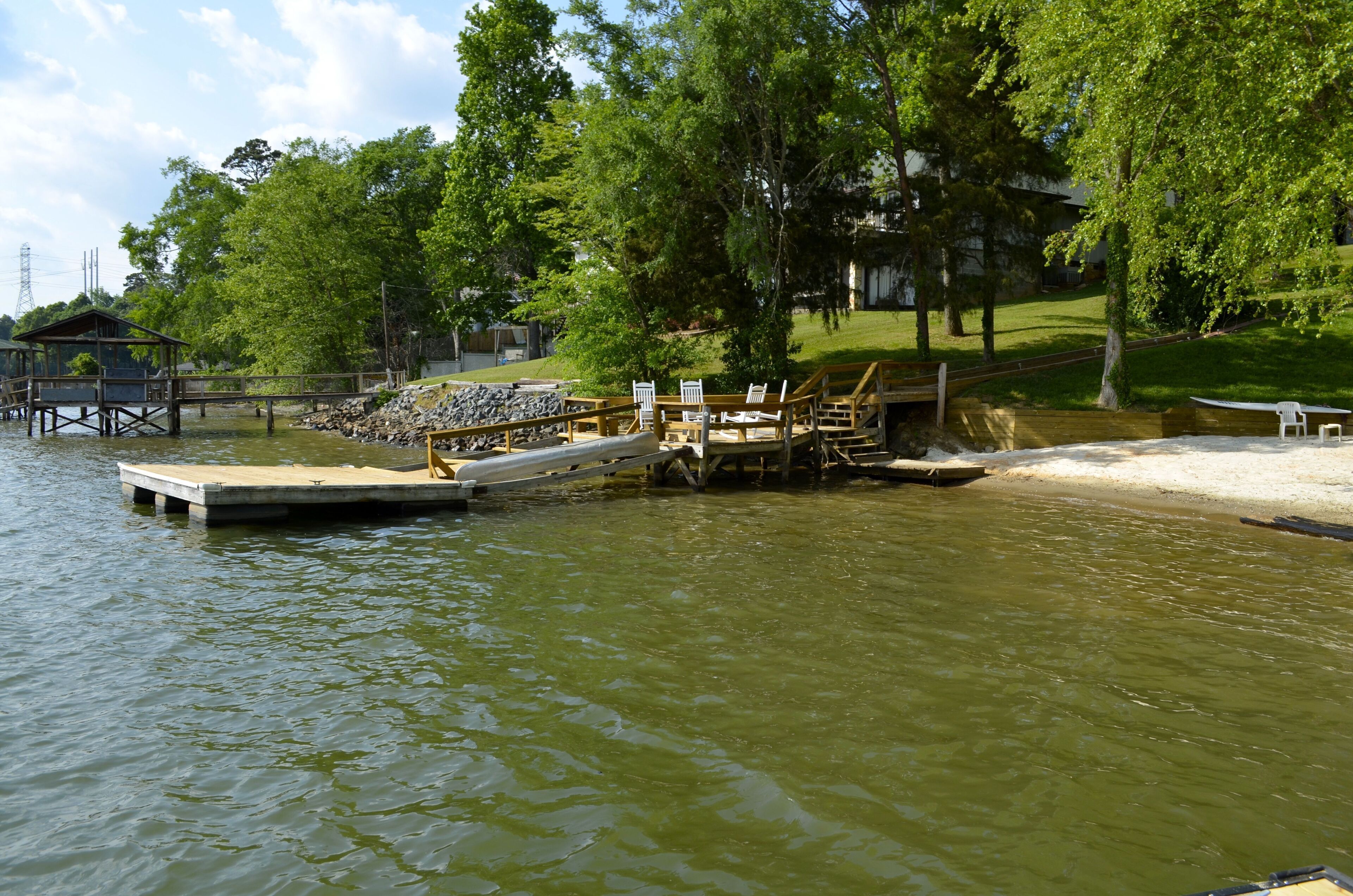 Une jetée s’avançant dans une étendue d’eau, avec une passerelle en bois et des chaises.