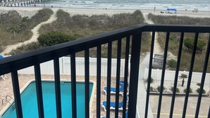 A pool with blue chairs, a beach with a pier, and a clear sky. - Lovely Oceanfront Condo with Gorgeous View with 3 Beds\3 Baths (North Myrtle Beach)