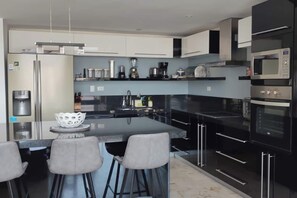 A modern kitchen with a central island, bar stools, and built-in appliances.