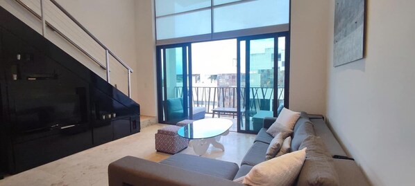 A modern living room with a sofa, ottoman, and a glass coffee table.