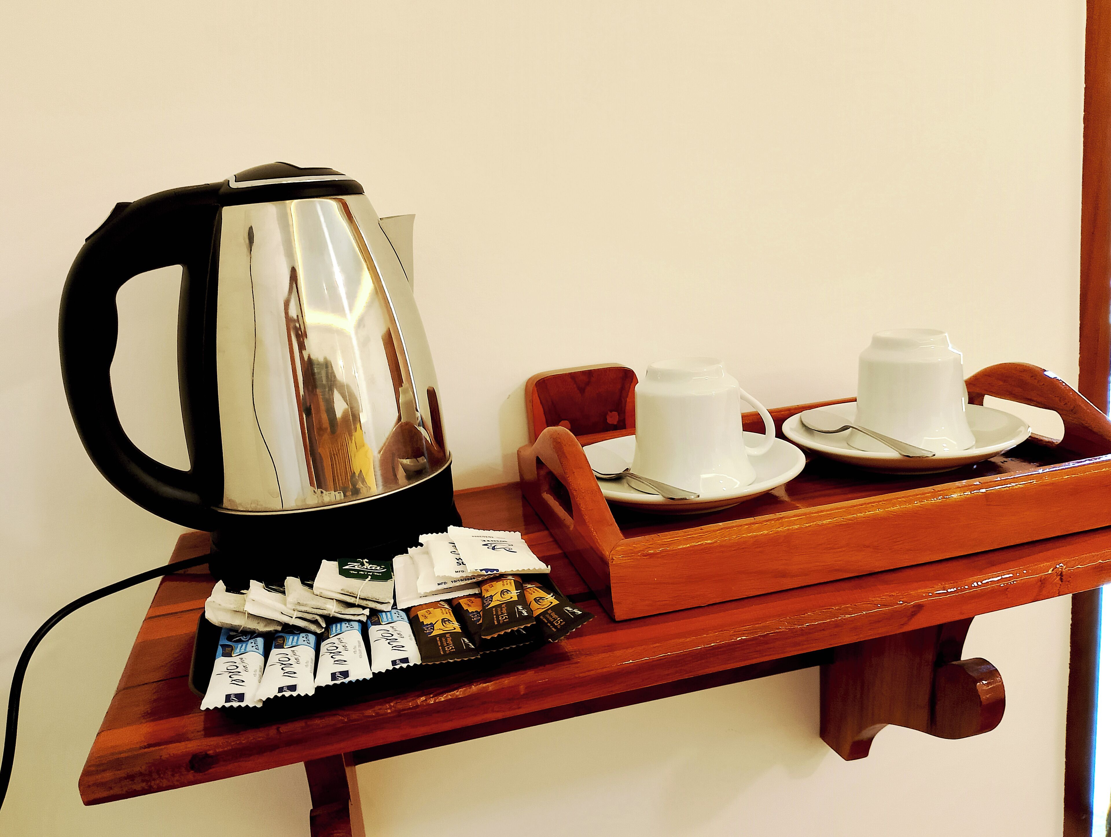 Een dienblad met een koffiezetapparaat, twee witte kopjes en een assortiment theezakjes.