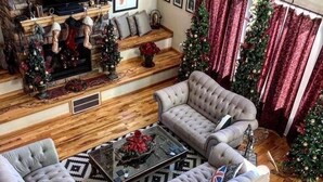 En hyggelig stue med pejs, to sofaer, et sofabord og julepynt.
