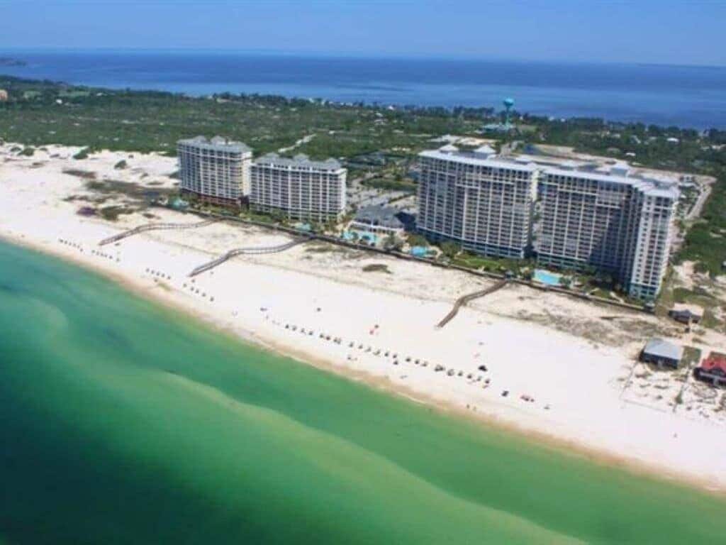 Un hotel costero con varios edificios altos, una playa y una vista despejada del océano.