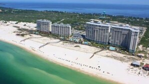 A coastal hotel with multiple high-rise buildings, a beach, and a clear view of the ocean.