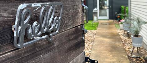 A wooden gate with a metal nameplate reading 'Rolls.'