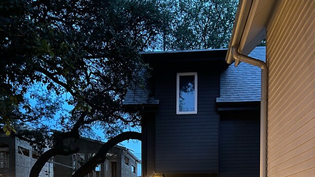 A residential backyard with a gravel pathway, two wicker chairs, a potted plant, and a small table. - Bright Contemporary Guest House with Private Patio, Walk to S Congress, Downtown (Austin)