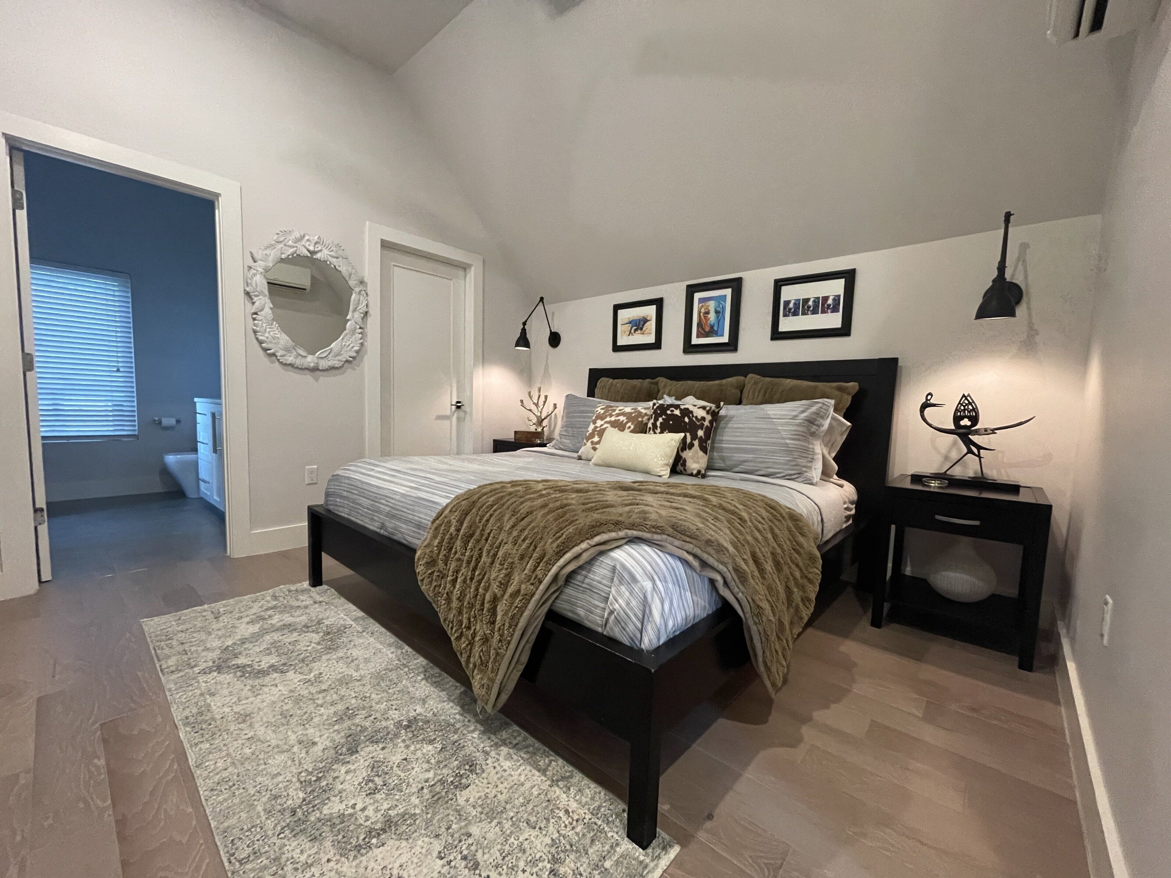 Une chambre à coucher avec un lit, des tables de chevet, un tapis et un miroir au mur.
