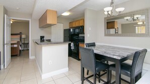 Una cocina moderna con una isla central, electrodomésticos negros y un comedor con una mesa y sillas de mármol.