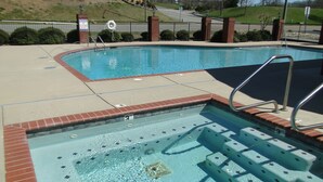 Una piscina con un jacuzzi, un puesto de socorrista y una valla.