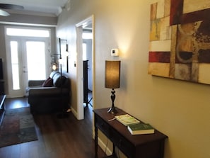 A living room with a dark-colored sofa, a lamp on a table, and a painting on the wall. - 50.00 October-stay gift card! Luxurious Condo, Riverfront w/ Mountain Views! (Sevierville)