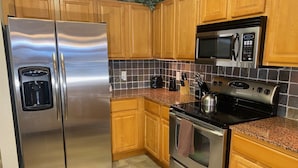 Una cocina con electrodomésticos de acero inoxidable, armarios de madera y salpicadero de azulejos.