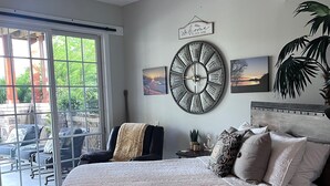 Un dormitorio con una cama grande, un ventilador de techo, vistas al exterior y un reloj de pared.