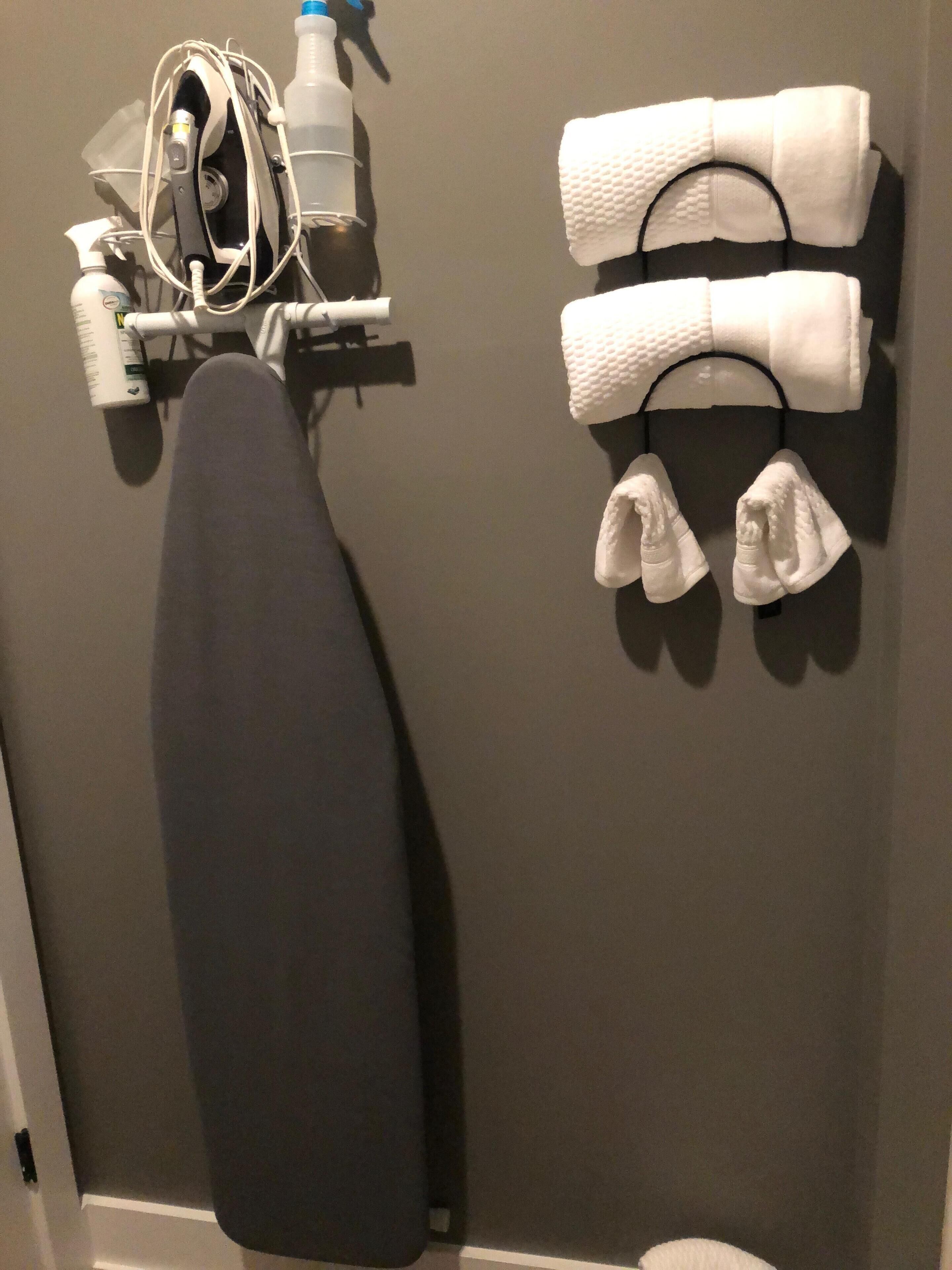 Un perchero de pared con dos toallas dobladas y dos pares de pantuflas blancas.