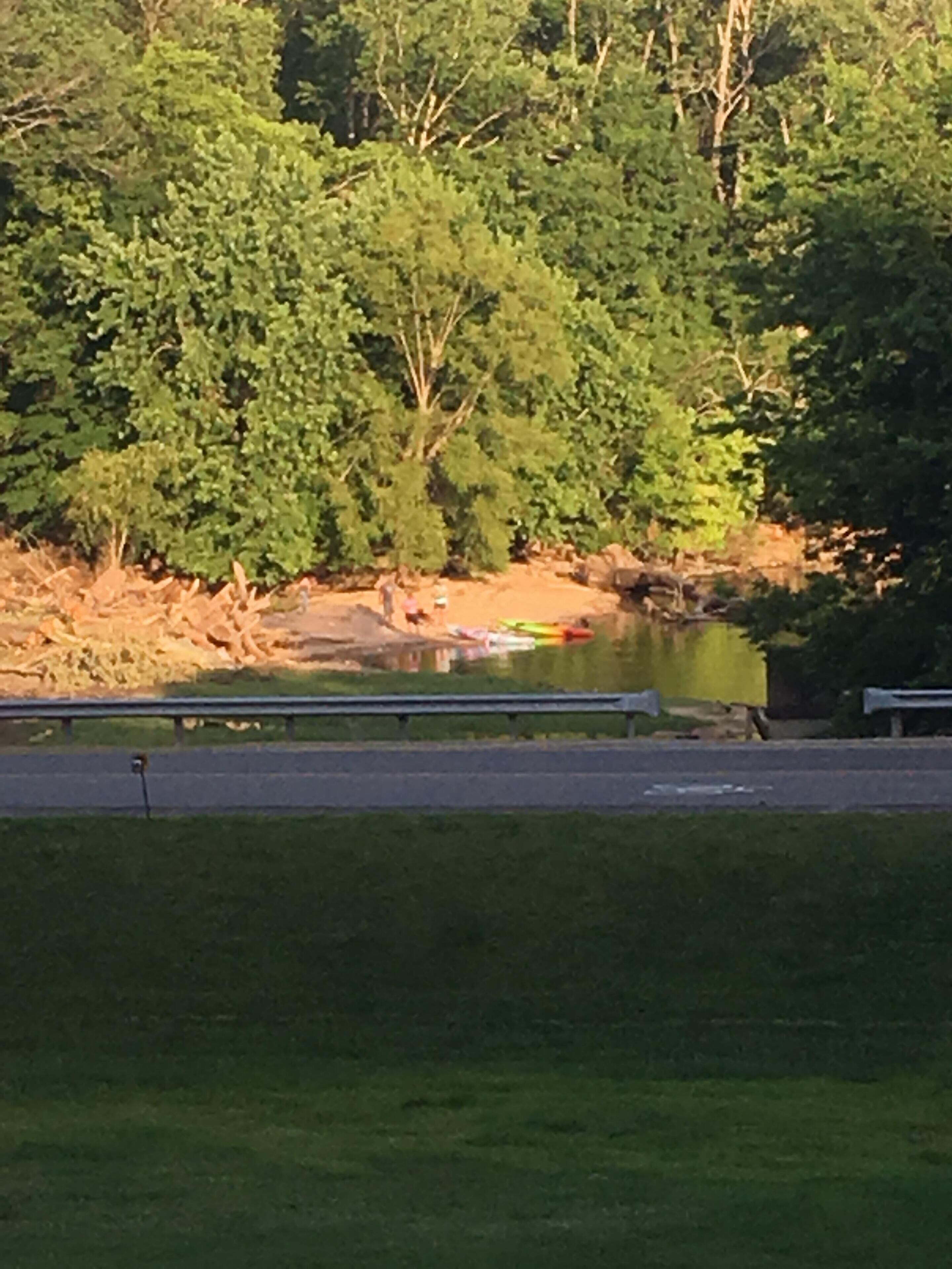 A riverbank with a bench and a kayak.