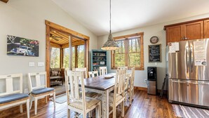 A kitchen with a wooden dining table, white chairs, a stainless steel refrigerator, and a water dispenser.