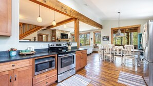 A spacious kitchen with wooden beams, a large island, and a dining area with natural light.