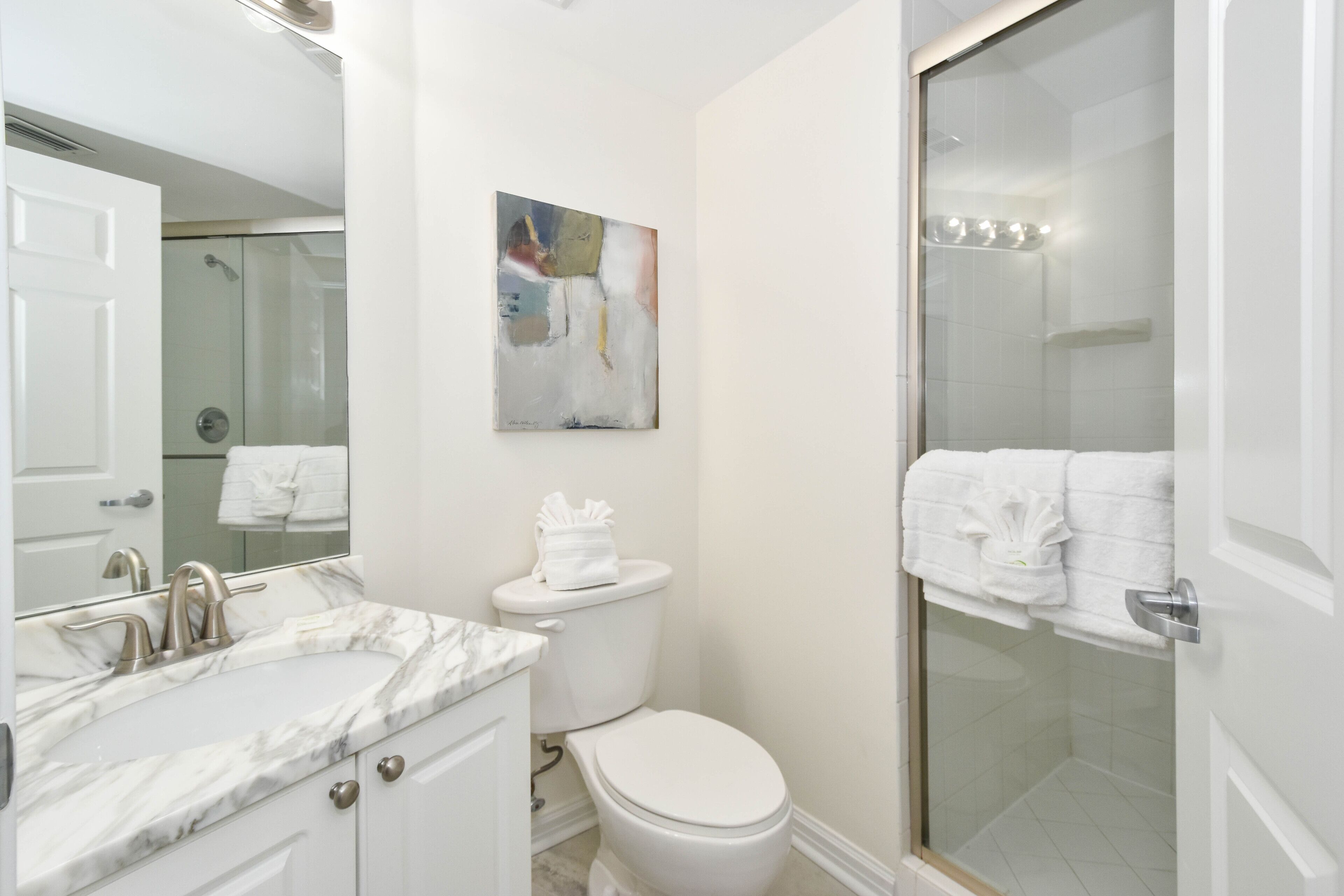 Une salle de bain moderne avec un lavabo en marbre, des toilettes et une douche à parois de verre.