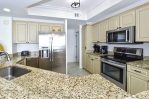 Cozinha moderna com bancadas de granito, eletrodomésticos de aço inoxidável e armários bege.