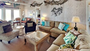 A cozy living room with a sofa, armchairs, a coffee table, and a wall-mounted decoration. - Blue Shamu | Oceanfront + Screened Porch! (Topsail Beach)
