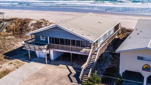 A beachfront property with a large house, a covered deck, and a view of the ocean. - Blue Shamu | Oceanfront + Screened Porch! (Topsail Beach)
