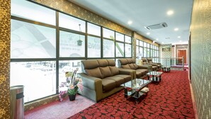 A hotel lobby with a red patterned carpet, leather sofas, and a large window with a view of the street. - Hamilton Hotel Kajang (Kajang)
