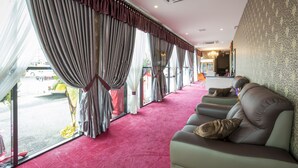 A room with a red carpet, a sofa with cushions, and a view of the street through large windows with curtains. - Hamilton Hotel Kajang (Kajang)