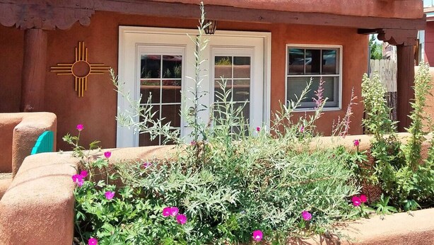 A rustic building with a stucco exterior, two white-framed doors, and a sun symbol on the wall.