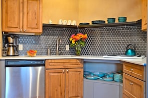 A kitchen with wooden cabinets, a dishwasher, a sink with a modern faucet, and a backsplash with hexagonal tiles. - Excellent Location & Divine Digs, Walk Everywhere! (Santa Fe)