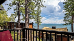 A balcony with a red chair, overlooking a lake with buildings and trees. - Star Harbor # 04 by Hauserman Rentals (Tahoe City)