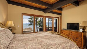 A bedroom with a large bed, a TV, and a view of a lake. - Star Harbor # 04 by Hauserman Rentals (Tahoe City)